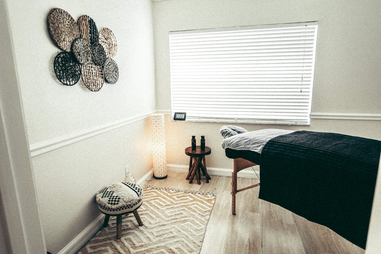Lit de massage vide dans une salle de thérapie paisible avec parquet.